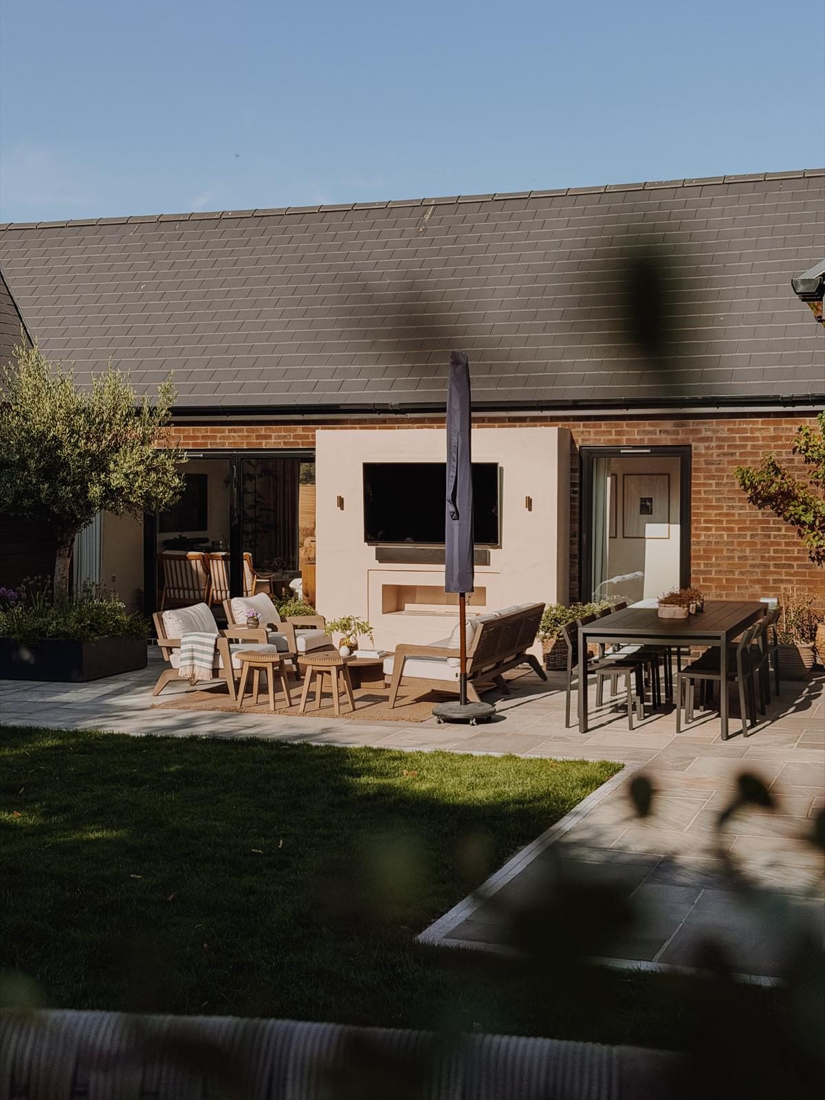Garden terrace with outdoor lounge, dining table and media wall